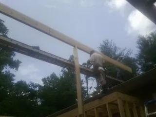 Carpenter setting a ridge beam over a new addition frame — Ice Dam Removal by Roofing Brothers in Sterling Heights