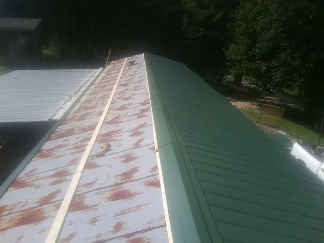 Old rusted panels beside newly installed green metal roofing — Wind Damage Roof Repair by Roofing Brothers in Sterling Heights