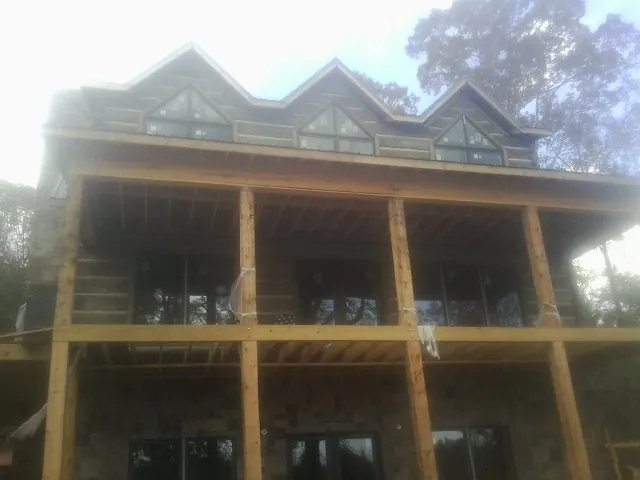 Dormers and porch framing on a large log home under construction — Roof Coating work by our crew in Sterling Heights