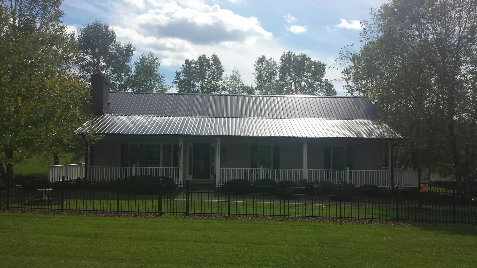 Gray metal roof on a brick ranch with a full width front porch — Gutter Guard Installation work by our crew in Sterling Heights